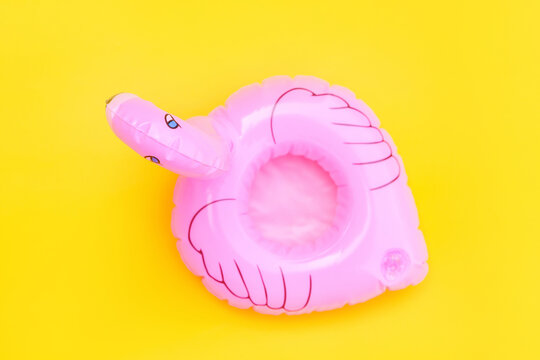 Summer beach composition. Simply minimal design with pink Inflatable flamingo isolated on yellow background. Pool float party, trendy celebrity fashion concept. Flat lay top view copy space.