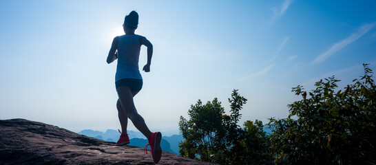 Young fitness woman trail runner running at mountain top