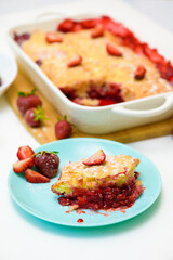 homemade strawberry cobbler made from ripe fresh strawberries. cut strawberry pie on a blue plate on a light background
