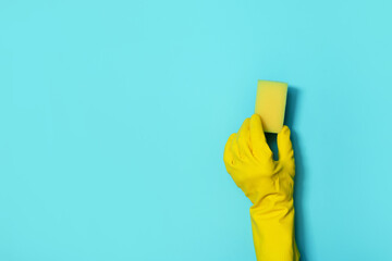 Hand in glove holding microfiber cleaning cloth, sponge on blue background. Copy space. Cleaning service concept. Spring general or regular clean up. Commercial cleaning company concept.