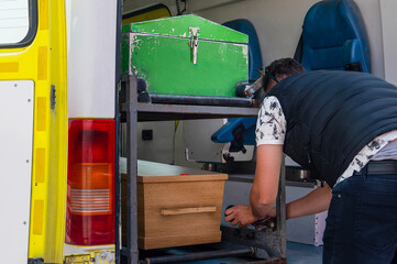 Man loads coffin in to the funeral coach