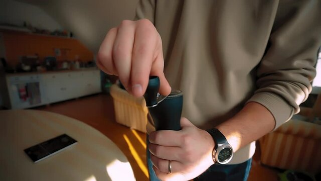 A man grinds coffee beans with a coffee grinder