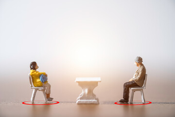 Old man and woman miniature people wearing face mask and sit down on chair by keep distance at public to prevent COVID-19 corona virus outbreak spread pandemic infection. Social distancing concept.