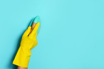 Hand in glove holding brush on blue background. Copy space. Cleaning house, cleaning toilet concept. Cleaning service concept. Household chemical cleaning products, brushes and supplies.