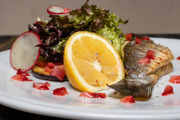 Baked sea fish with vegetables radish, lettuce, lemon and tomatoes. Good proper nutrition, weight...