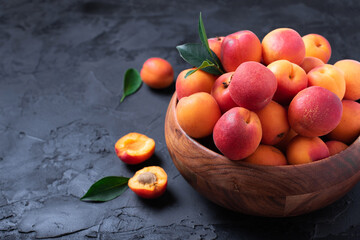 Ripe apricots on black background. Top view, copy space. Fruit banner. Healthy vegetarian food, detox or diet concept. Fruit summer concept. Bowl of harvested apricots for jam