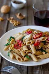 Italian penne pasta with tomatoes, spinach, parmesan cheese, garlic and nuts. Healthy eating. Vegetarian food.