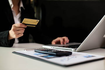 Gorgeous businesswoman sititng at cafe using mobile banking application on her gadget while paying bills using free internet connection. Busy woman sitting at restaurant with credit card and phone