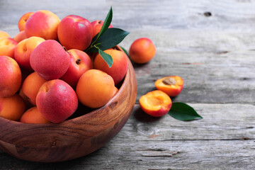 Ripe apricots with leaves on wooden background. Top view, copy space. Fruit banner. Healthy vegetarian food, detox or diet concept. Fruit summer concept. Bowl of harvested apricots for jam