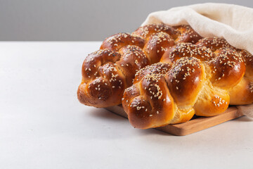 Homemade Challah bread with white cover, Jewish cuisine. Main ingredients are eggs, white flour, water, sugar, salt and yeast. Decorated with sesame and poppy seeds. Copy space.