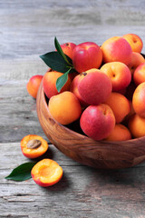 Ripe apricots with leaves on wooden background. Top view, copy space. Fruit banner. Healthy vegetarian food, detox or diet concept. Fruit summer concept. Bowl of harvested apricots for jam