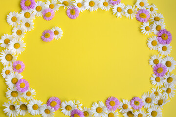 Obraz premium Arrangement of daisy flowers and pink flowers on a yellow background with a central space for design. Top view