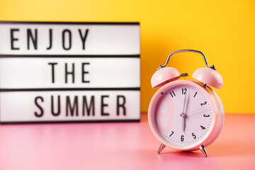 Enjoy the summer. Detail close up of the old pink vintage alarm clock on colour background.