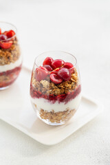 Granola Parfait with Yogurt, oat granola, fresh cherry, jam and honey in tall glass. Healthy dessert. Low depth of field, selective focus.