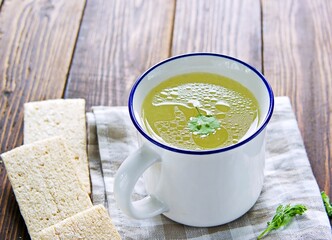 Chicken or meat broth in a white ceramic mug with a blue rim.