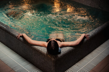 Conception of bodycare. Beauty and body care. View of a young woman enjoying whirlpool bath....