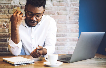 Thoughtful male administrative manager in trendy outfit and glasses planning and coordinating...