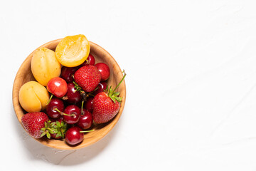 Healthy organic fruit in a wooden bowl on white concrete background with copy space for your design.