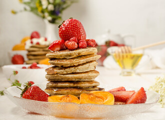Pancakes with honey, strawberries and fruits close-up. Tasty summer breakfast.