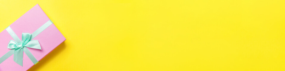 Christmas New Year birthday valentine celebration present romantic concept. Simply minimal design pink gift box isolated on yellow colorful background. Flat lay top view copy space, banner