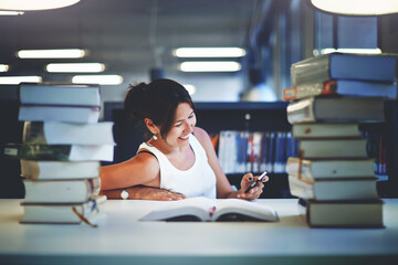 Working hard for great grades, asian smiling student girl holding cell phone sitting in university...