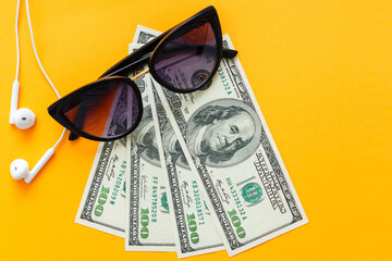 stylisch brown sunglasses on a pile of money, isolated on yellow