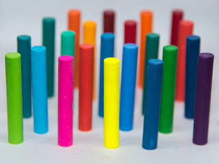 Crayons of different colours,  haphazardly displayed on a white background standing upright with use of selective focus.