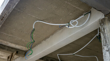 White PVC plastic wiring cable installation for house construction. Power cables on renovation house ceiling.