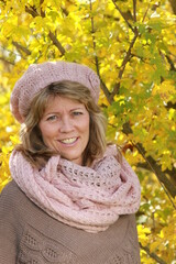 Happy mature woman with scarf and cap in autumn