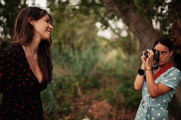 Two young women taking photos each other in the forest