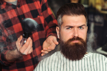 Bearded man getting haircut by hairdresser. Brutal guy sitting in barber chair. Vintage barbershop,...