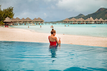 Beautiful blonde girl posing in pool on tropical island