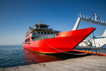 Red ferry boat with an open ramp and empty car deck, moored to the harbour, Thassos Island, Greece