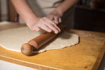 preparing  dough for baking with hands and roler 