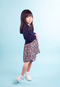 Studio portrait of a cute asian little girl with posing. isolated in blue background.
