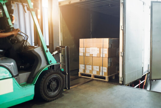 Workers Driving Forklift Tractor Loading Cargo Pallets into Container Trucks. Shipping Warehouse. Delivery Service Shipment Boxes. Supply Chain Goods. Warehouse Cargo Logistics Transport.	