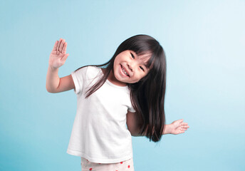 Studio portrait of a cute asian little girl with spread hands and smiling. isolated in blue background.