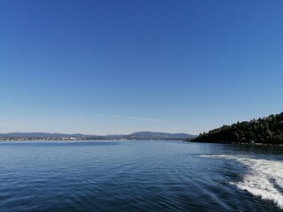 Beautiful calm day on the sea with clear blue sky and island with pine trees
