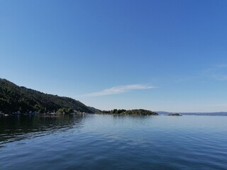 Beautiful calm day on the sea with clear blue sky and island with pine trees