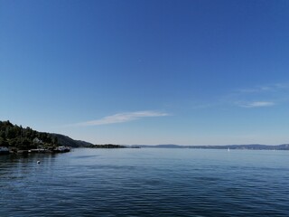 Fototapeta premium Beautiful calm day on the sea with clear blue sky and island with pine trees