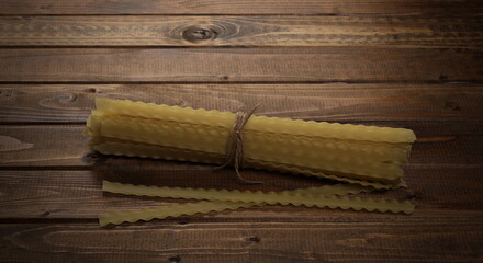 Mafaldine pasta on wooden plank table, background and texture