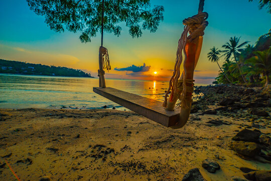 Beautiful sunset over the beach with coconut palm tree and hanging Woodden swing - Koh Phangan,Thailand