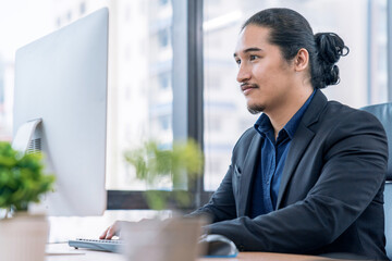 Asian businessman sitting in office and working on desktop pc.