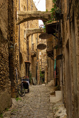 Narrow and mysterious road in a mountain town. Narrow street with houses, walls and ladder made of...