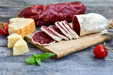 Italian  dried   artisan  pork salami,parmesan cheese , cherry  tomatoes and fresh basil on wooden background .Rustic  home made food