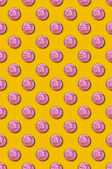 Pattern of cupcakes with pink cream on a yellow background. The concept of a holiday, party, sweets, unhealthy food. Top view, flat lay, minimalism.