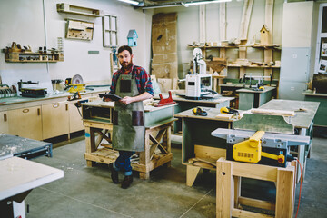 Confident joiner with notebook in workshop