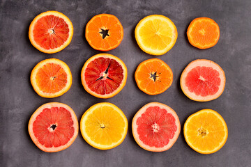 Bright layout of circles of red and orange oranges, tangerines and grapefruit on a gray background
