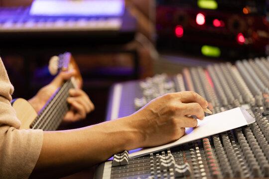 male artist, songwriter writing a song on white paper in recording studio