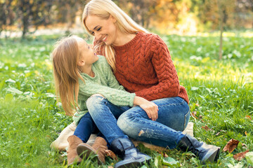 Naklejka na ściany i meble Happy smiling young caucasian mother and little daughter hugging each other outdoors. Happy family outdoor.